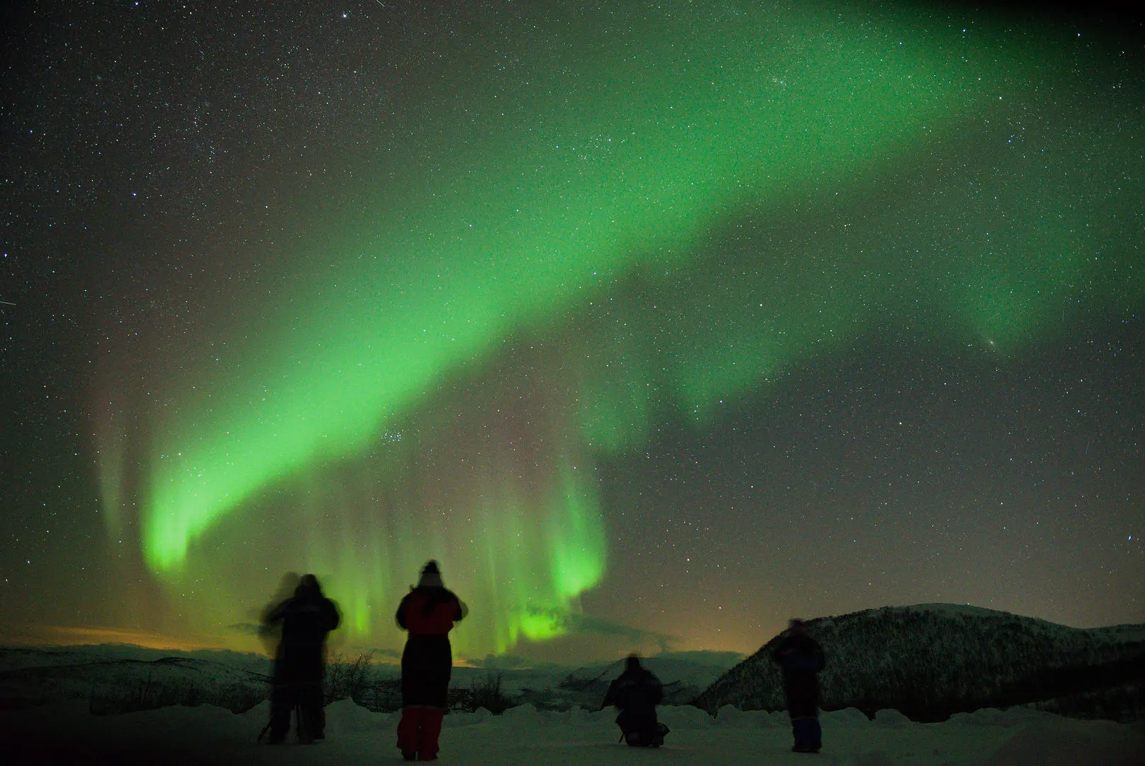 Guests watching a bright aurora by the shore